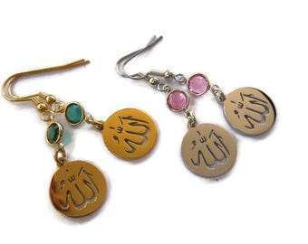 May include: Gold and silver earrings with a pendant featuring the Arabic word "Allah" in a decorative script. The earrings are adorned with green and pink crystals.