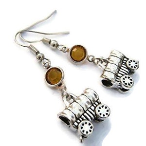 May include: Silver earrings with a wagon charm and amber-colored glass beads.