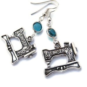 May include: Silver earrings with a blue gemstone and a charm of a vintage Singer sewing machine.