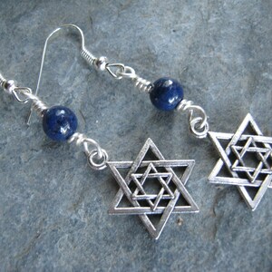 Pu&ograve; includere: Orecchini d'argento con una pietra preziosa blu e un ciondolo a forma di stella di David in argento.