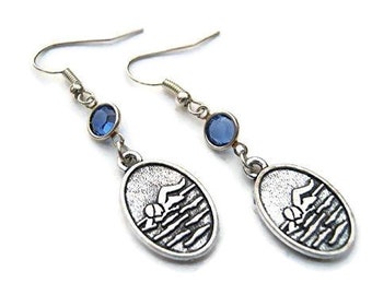 May include: Silver tone earrings with a swimmer design and blue crystal accents.