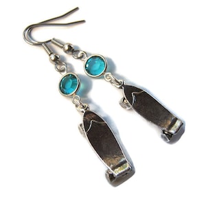May include: A pair of silver earrings with blue crystal accents and a skateboard charm.