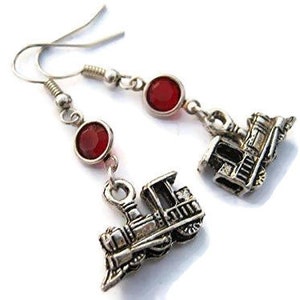 May include: Silver dangle earrings with red gemstone accents and a silver train charm.