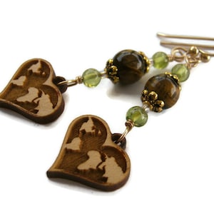 May include: A pair of wooden heart earrings with a world map design, featuring tiger's eye and green gemstone beads.