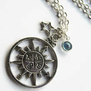 Puede incluir: Collar de plata con un dije de brújula, un dije de estrella y un dije de piedra preciosa azul.