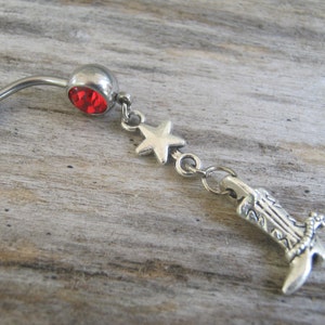 May include: Silver belly button ring with a red gem, a star charm, and a boot charm.
