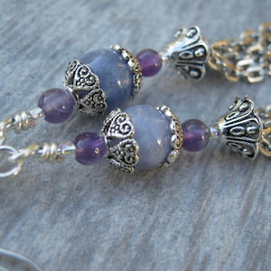 May include: Silver earrings with blue and purple gemstone beads and silver chain tassels.