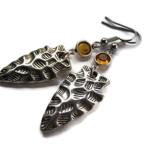 May include: Silver arrowhead earrings with amber-colored glass beads. The arrowheads have a textured surface.