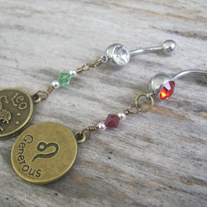 May include: Two silver body jewelry pieces with charms. One charm is a bronze circle with the zodiac symbol for Leo and the word "Leo". The other charm is a bronze circle with the zodiac symbol for Virgo and the word "Generous".