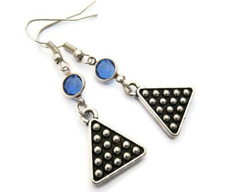 May include: Silver earrings with a triangle shape and a textured surface. Each earring has a blue crystal.