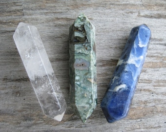 May include: Three crystal wands, one clear quartz, one green and white, and one blue with white swirls.