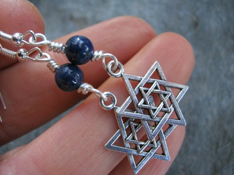 Pu&ograve; includere: Orecchini d'argento con un ciondolo a forma di stella di David e perline di lapislazzuli blu.