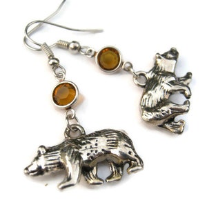 May include: Silver bear charm earrings with amber colored crystal accents.