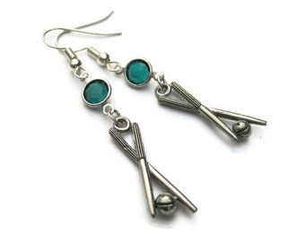 May include: Silver earrings with a pair of crossed drumsticks and a teal blue crystal charm.