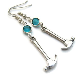 May include: Silver hammer earrings with turquoise blue crystal accents.
