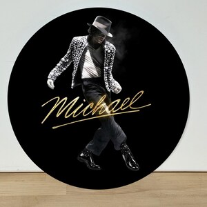 May include: A circular black wall art piece featuring a monochrome image of a performer in a fedora, white shirt, and a sequined jacket, captured in a dynamic dance pose. The name Michael is written across the center in a gold cursive script.