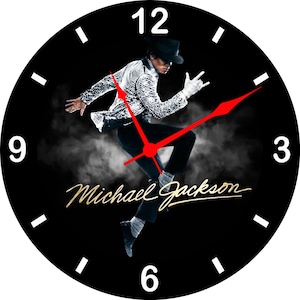 May include: Black wall clock featuring a dynamic image of Michael Jackson in a silver sequined jacket and black pants. The clock hands are red, and the numbers are white. The singer's signature is in gold.