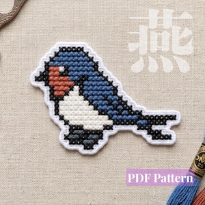 May include: A cross-stitch design of a bird with blue wings, a white chest, and a reddish-brown face. The bird is outlined in black thread on white fabric. The text PDF Pattern is visible in the lower right corner, and a Chinese character is visible in the upper right.