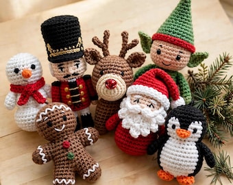 May include: A collection of six crocheted holiday figures including a white snowman with a red scarf, a nutcracker in a black hat, a brown reindeer with a red nose, a green elf, a Santa Claus with a white beard, and a black and white penguin.