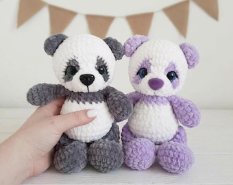 May include: Two plush stuffed animals made of soft yarn. One is a panda with white and dark gray fur, black eyes, and a black nose. The other is a bear with white and light purple fur, blue eyes, and a purple nose. Both have round ears.