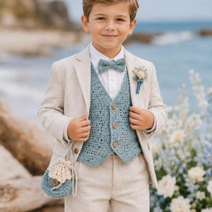 Puede incluir: Un traje beige compuesto por chaqueta y pantalón, combinado con una camisa blanca de cuello, un chaleco azul de ganchillo con tres botones de madera, una pajarita azul de ganchillo a juego y una pequeña bolsa de ganchillo azul y beige.