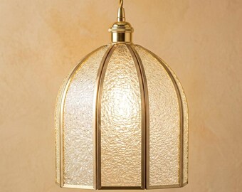 May include: A dome-shaped pendant light fixture featuring textured, clear glass panels framed in a polished brass metal structure. The lamp hangs from a matching brass cord and includes a central light source that illuminates the glass.