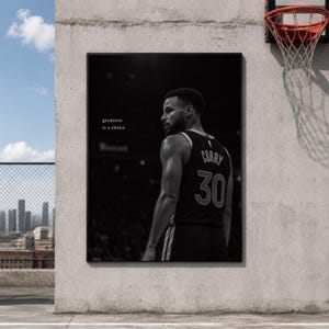Puede incluir: Una impresión de arte mural enmarcada en blanco y negro que muestra a un jugador de baloncesto con una camiseta con el nombre CURRY y el número 30 en la espalda. El texto greatness is a choice está impreso en blanco en el lado izquierdo.