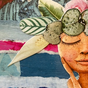 May include: A mixed media collage artwork featuring a stylized face with closed eyes and freckles, adorned with a crown of paper cut-out green leaves and pink flowers, set against a layered background of blue, white, and magenta paper strips.