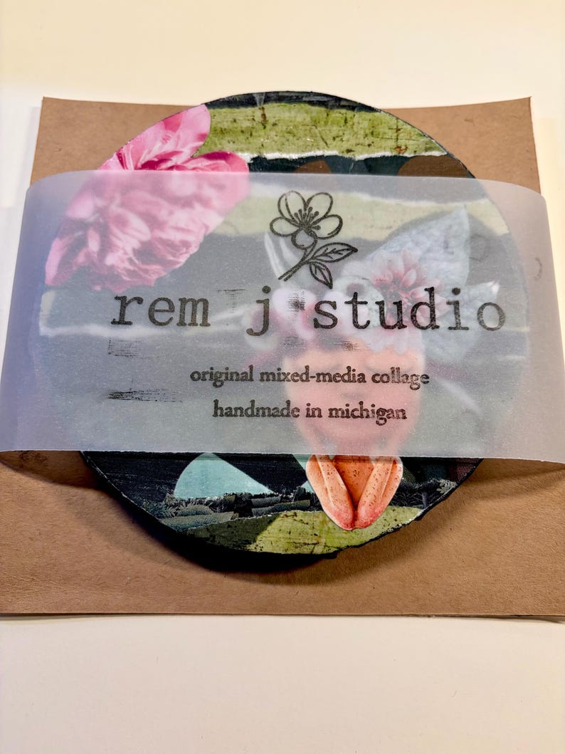 May include: A circular mixed-media collage featuring pink floral and green striped elements, wrapped in a translucent band printed with the text 'rem j studio', 'original mixed-media collage', and 'handmade in michigan' with a flower icon.