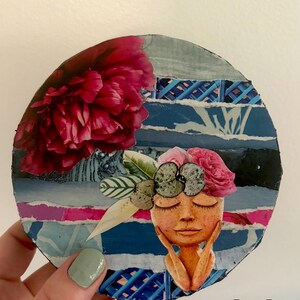 May include: A circular collage art piece measuring 5 x 5 inches, featuring a large dark pink peony, a stylized face with closed eyes resting on hands, and a floral headpiece. The background consists of layered blue and white paper strips.