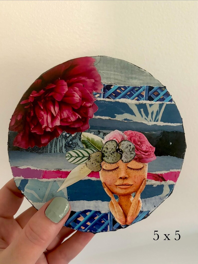 May include: A circular collage art piece measuring 5 x 5 inches, featuring a large dark pink peony, a stylized face with closed eyes resting on hands, and a floral headpiece. The background consists of layered blue and white paper strips.