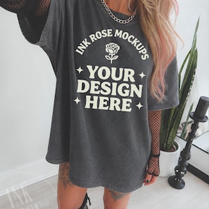 Może przedstawiać: Ciemnoszary t-shirt oversize z białym nadrukiem graficznym z napisem INK ROSE MOCKUPS, ikoną róży oraz tekstem YOUR DESIGN HERE otoczonym czteroramiennymi gwiazdami. Koszulka posiada okrągły dekolt i krótkie rękawy.