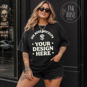 May include: A black short-sleeve t-shirt featuring cream-colored text that reads INK ROSE MOCKUPS, a rose icon, and the words YOUR DESIGN HERE, accented by four-pointed stars. The shirt has a relaxed fit and is worn with black denim shorts.