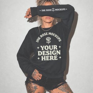 May include: A black long-sleeve sweatshirt featuring white text and a rose graphic. The chest displays the words INK ROSE MOCKUPS, a rose icon, and YOUR DESIGN HERE with four-pointed stars. The left sleeve also features INK ROSE MOCKUPS text.