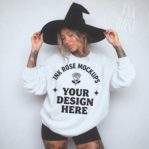 May include: A light gray crewneck sweatshirt featuring black text that reads INK ROSE MOCKUPS, a rose graphic, and the words YOUR DESIGN HERE, accented by two four-pointed stars. The garment is paired with a black pointed witch hat.