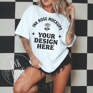 May include: A white short-sleeved t-shirt featuring black text that reads INK ROSE MOCKUPS with a rose icon above the words YOUR DESIGN HERE and two four-pointed star icons on the sides. The shirt has a loose fit and a crew neckline.