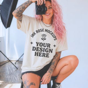 May include: A beige short-sleeve t-shirt featuring black text that reads INK ROSE MOCKUPS, a small rose illustration, and the text YOUR DESIGN HERE, accented by two four-pointed star symbols centered on the chest area of the garment.