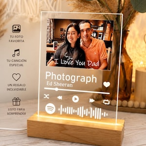 May include: A rectangular clear acrylic plaque mounted on a light-colored wooden base. The plaque features a printed photograph of two people, the text "Photograph" by "Ed Sheeran," a music playback interface, and a Spotify code graphic.