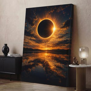 Op de afbeelding: Een rechthoekige canvas print met een totale zonsverduistering boven een kalm wateroppervlak. De afbeelding toont een donkere maan tegen een heldere gouden zon, met oranje en donkerblauwe wolken die reflecteren in het wateroppervlak.