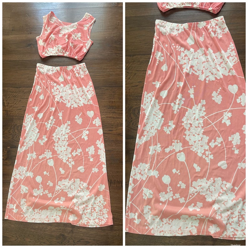 May include: A two-piece outfit with a pink crop top and a matching maxi skirt. The skirt and top have a white floral pattern.