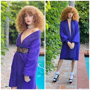 Könnte beinhalten: Ein lilafarbener, flauschiger Cardigan mit tiefem V-Ausschnitt und langen Ärmeln. Der Cardigan wird über einem passenden lilafarbenen, flauschigen Kleid mit Gürtel getragen. Das Model trägt weiße Socken und schwarze Plateau-Heels.