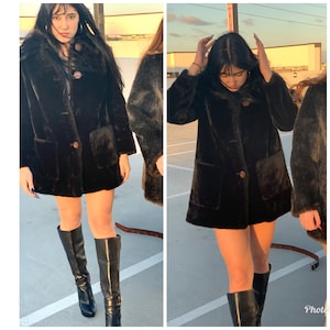 May include: Two women wearing brown faux fur coats with large pockets and black knee-high boots. The coats have a button closure and a collar.
