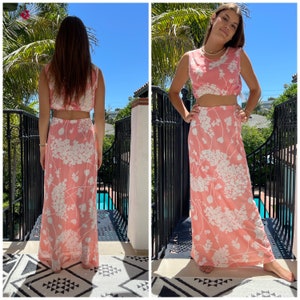 May include: A pink and white floral print two-piece outfit with a sleeveless crop top and a maxi skirt.