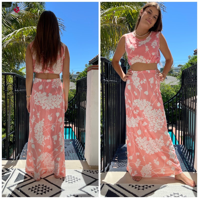 May include: A pink and white floral print two-piece outfit with a sleeveless crop top and a maxi skirt.