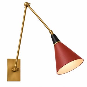 Può includere: Una lampada da parete con braccio orientabile dotata di una piastra rettangolare in ottone, un lungo braccio regolabile in ottone e un paralume conico. Il paralume è rifinito in rosso intenso con una sezione superiore nera e interno bianco.