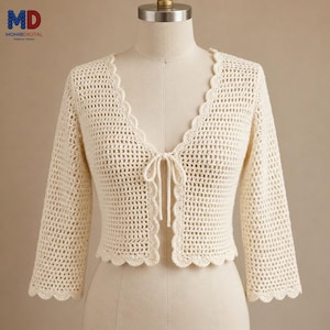 May include: A cream-colored, open-front crochet cardigan featuring a delicate scalloped edge along the neckline, front opening, and sleeve cuffs. The garment has three-quarter length sleeves and a single tie closure at the center of the chest.