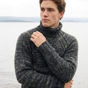 Puede incluir: Un jersey de cuello alto gris oscuro con un patrón de punto texturizado. El jersey tiene un cuello alto y mangas largas. El estilo general es informal y adecuado para climas más fríos.