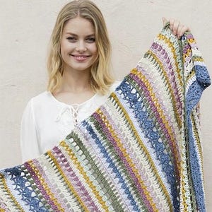 Puede incluir: Una manta de ganchillo rectangular que presenta un patrón repetitivo de rayas verticales en varios colores, incluyendo amarillo mostaza, verde salvia, rosa viejo, crema y azul pizarra, con intrincados detalles de puntos calados.