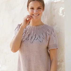 Puede incluir: Una blusa de punto de color rosa empolvado con mangas cortas, que presenta un cuello redondo con un intrincado patrón de encaje inspirado en hojas en el canesú. La prenda tiene cuello, puños y dobladillo acanalados, confeccionada en hilo liso.