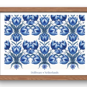 Op de afbeelding: Een ingelijste print met een herhalend patroon van blauwe en witte tulpen in de stijl van Delfts blauw aardewerk. Het ontwerp bevat symmetrische bloemmotieven op een witte achtergrond met de tekst Delftware • Netherlands onderaan.